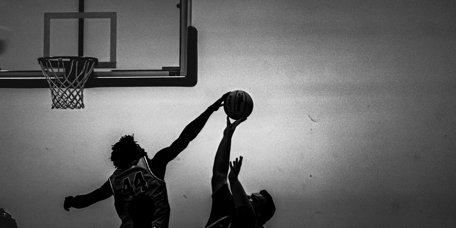Black and white image of basketball player blocking a shot.